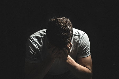 man holding his face while sitting on chair thumbnail