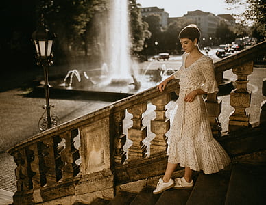 woman standing on stairs near fountain and light post during daytime thumbnail