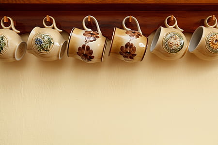 six assorted-color floral ceramic teacups hanged on brown wooden wall-mounted shelf with hooks thumbnail
