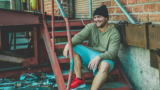 man sitting down on brown metal stair outside thumbnail