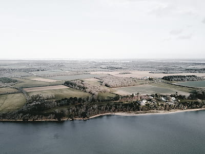aerial view of farm beside body of water thumbnail