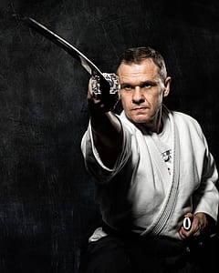 man wearing white karate gi holding sword thumbnail