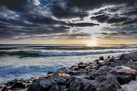 landscape photography of coastal rocks under cloudy sky thumbnail