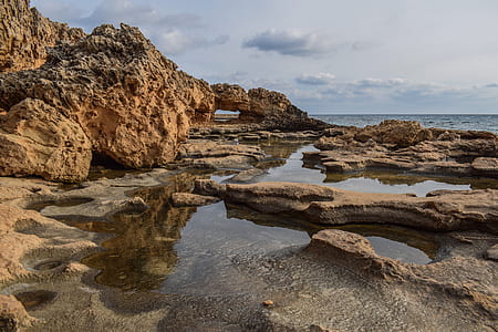 brown rock formation near body of water thumbnail