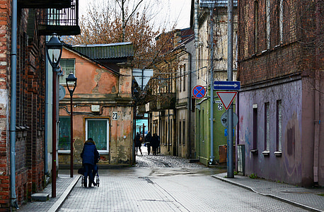 photo of woman walking on pathway between buildings thumbnail