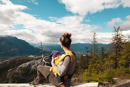 Woman Carrying Baby Sitting on Gray Surface thumbnail