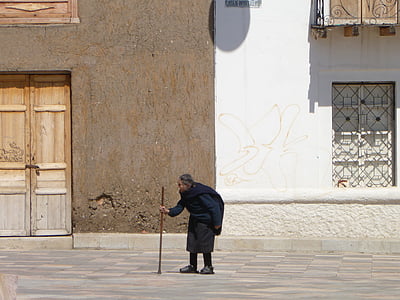 person walking on street while holding walking cane thumbnail