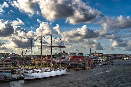 white boat near buildings under blue and grey sky at daytime thumbnail