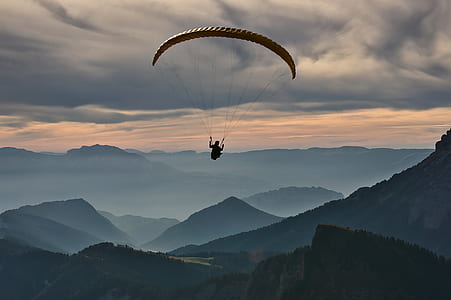 person riding parachute over mountains during daytime thumbnail