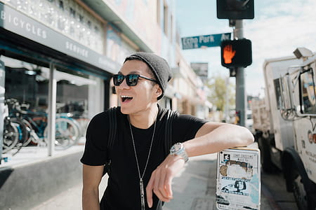 man leaning on white signboard beside street during daytime thumbnail