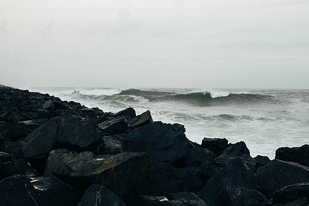 black boulders beside body of water thumbnail