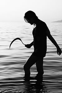 silhouette of woman holding sickle in body of water thumbnail