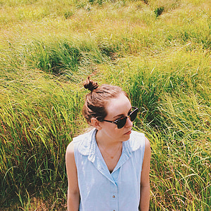 woman wearing sunglasses standing on grass fields thumbnail