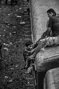 man sitting on train while helping man to climb thumbnail