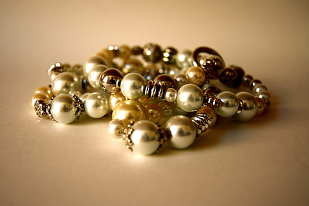 beaded gold-colored bracelets on beige surface thumbnail