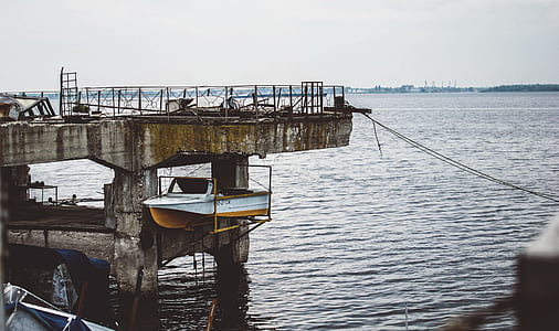 white and yellow boat lift on yellow metal frame under gray concrete dock thumbnail