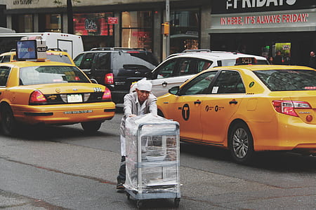 man pushing cart on road thumbnail