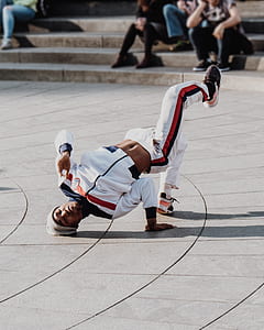 man wearing white and black jacket doing brake dance during daytime thumbnail