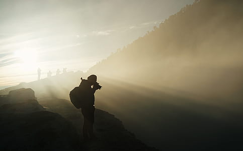 photography of man in silhouette holding camera thumbnail