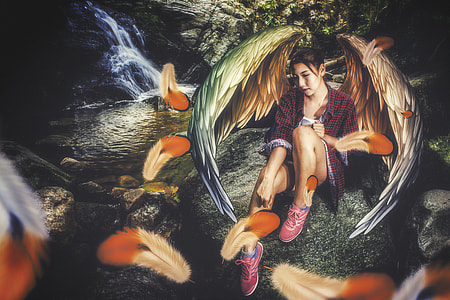 girl with red cardigan sitting on river rock during daytime thumbnail