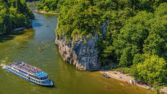 blue and white ship on body of water near gray rock formation during daytime thumbnail