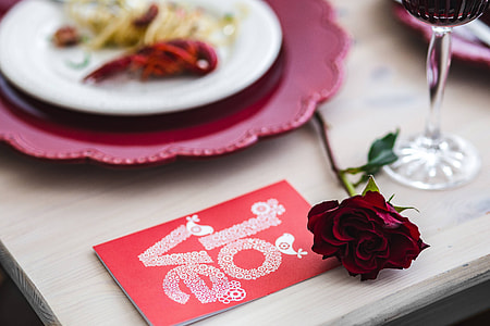 Fancy dinner with seafood pasta, crayfish and red wine by the table decorated with roses thumbnail