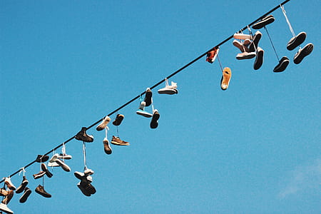 worm's eye view photography of shoes hanged on wire on top thumbnail