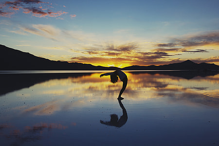 silhouette of person standing on body of water thumbnail