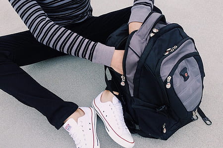 person searching inside black and gray backpack thumbnail