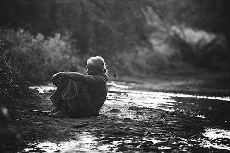 gray scale photo of woman sitting near grass field thumbnail