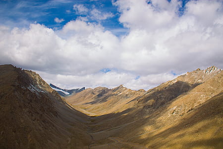 brown hills under cloudy sky at daytime thumbnail