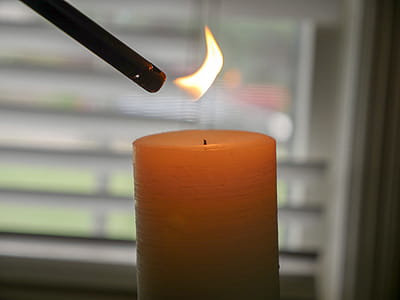 White candle being lit by a flame. thumbnail