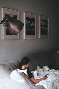 woman sitting on sofa while reading book thumbnail