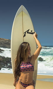 woman leaning on surfboard under blue sky thumbnail