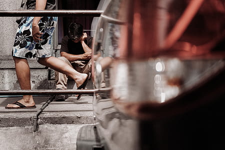man wearing floral shorts passing by man sitting on stair thumbnail