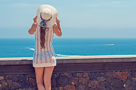 woman in white sleeveless mini dress near body of water during daytime thumbnail