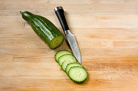 sliced cucumber and black handled knife on brown wooden surface thumbnail