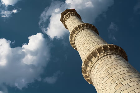 low-angle photography of beige concrete lighthouse tower under blue and white sky thumbnail