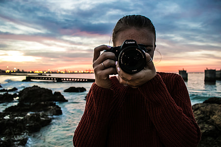 person capturing photo using black Canon DSLR camera under cloudy sky thumbnail