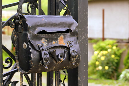 black leather handbag hanging on black metal gate at daytime thumbnail