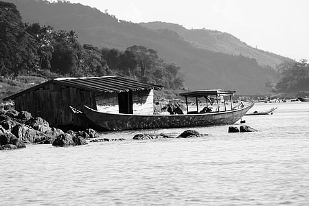 greyscale photography of boat on water near house thumbnail