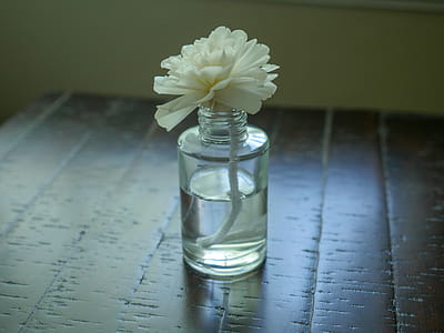 Essential oil diffuser with a flower on top, sitting on a wooden desk. thumbnail