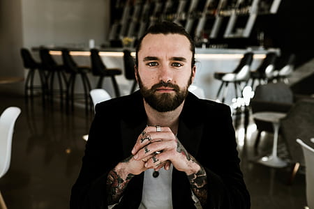 selective focus photo of man sitting on chair wearing black suit jacket thumbnail
