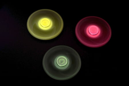 three yellow, red, and green turning fidget spinners with black background thumbnail