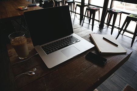 Macbook Pro turned off beside black smartphone on brown wooden table thumbnail