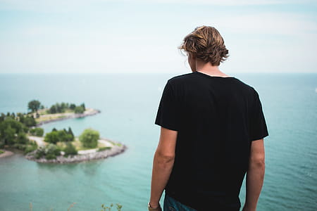 A young caucasian man looks at the ocean from the top thumbnail