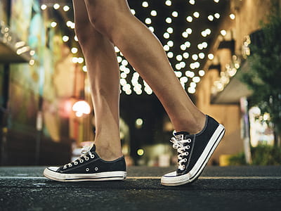 person wearing black sneakers walking under string lights thumbnail