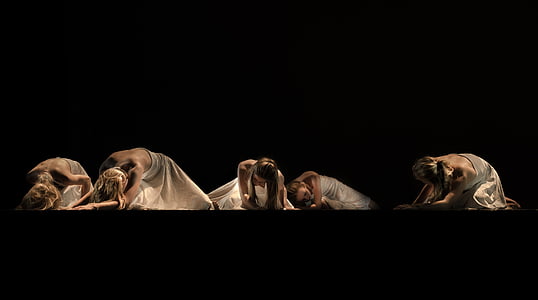five woman in white dresses sitting on dark surface thumbnail