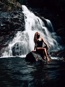 woman sitting on rock in front of waterfalls thumbnail