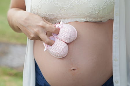 maternity photo-shot holding pink knitted shoes thumbnail